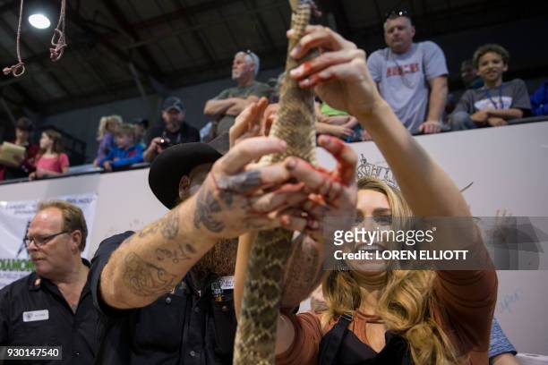 "Miss Texas" Margana Wood skins a rattlesnake under the guidance of Red Hurd II during the Sweetwater Rattlesnake Roundup at Nolan County Coliseum?...
