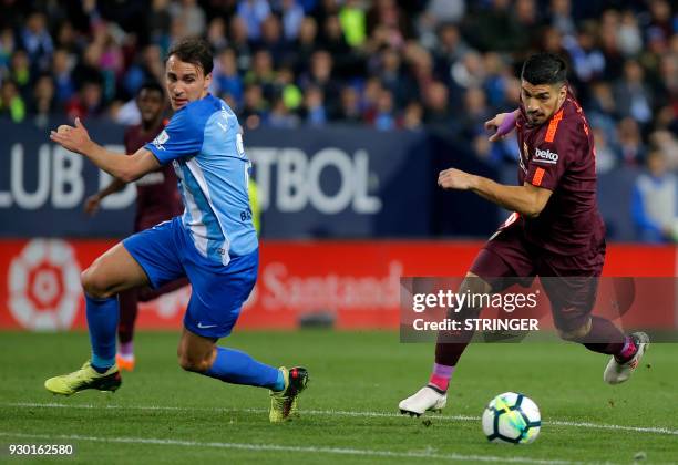 Malaga's Spanish defender Ignasi Miquel vies with Barcelona's Uruguayan forward Luis Suarez during the Spanish league football match between Malaga...