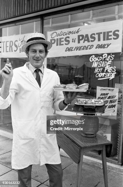 Customers waiting for their meat pies to warm up on the Calor gas cooker provided by Peter Neville, outside his shop at The Centre, Higher Folds in...