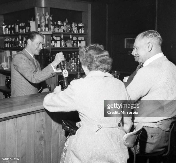 Former Middlesbrough footballer Wilf Mannion serving customers at the bar in his pub, 19th April 1959.