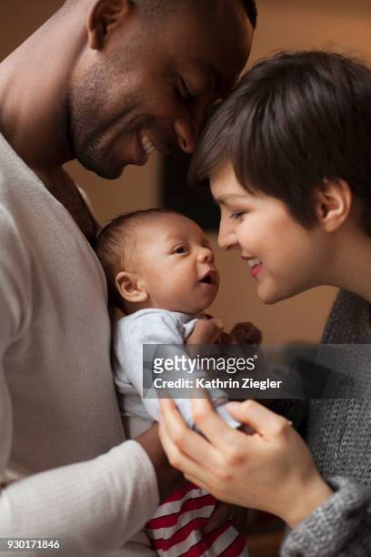 a happy young family, mother and father smiling at their newborn baby - cute black newborn babies stock-fotos und bilder