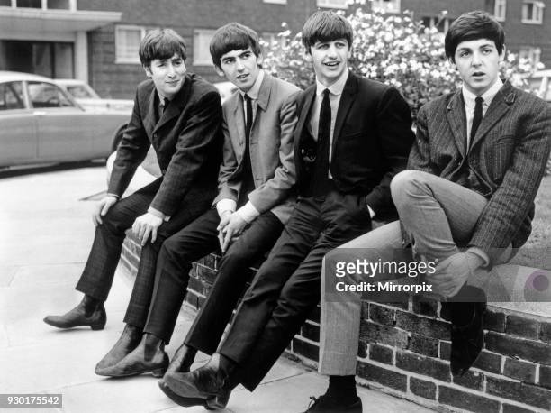 The Beatles pose sitting on a wall. Left to right: John Lennon, George Harrison, Ringo Starr, and Paul McCartney, 9th September 1963.