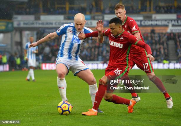 Aaron Mooy of Huddersfield Town is tackled by Martin Olsson of Swansea City during the Premier League match between Huddersfield Town and Swansea...