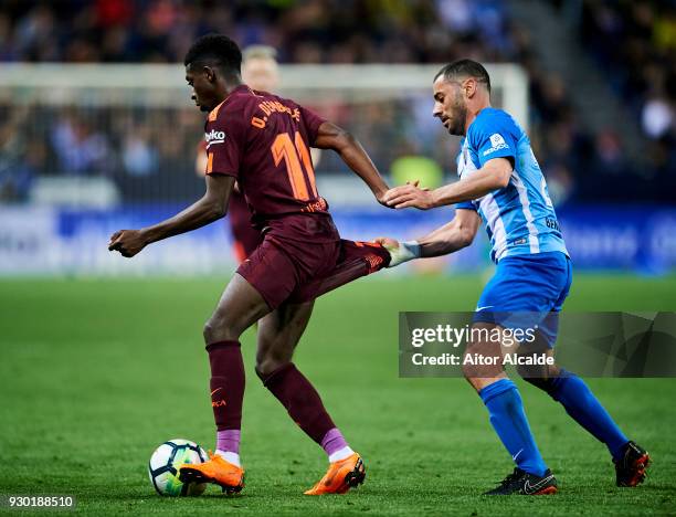 Ousmane Dembele of FC Barcelona duels for the ball with Medhi Lacen of Malaga during the La Liga match between Malaga and Barcelona at Estadio La...