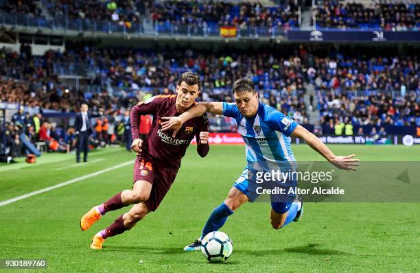 Philippe Coutinho of FC Barcelona duels for the ball with Federico Ricca of Malaga during the La Liga match between Malaga and Barcelona at Estadio...