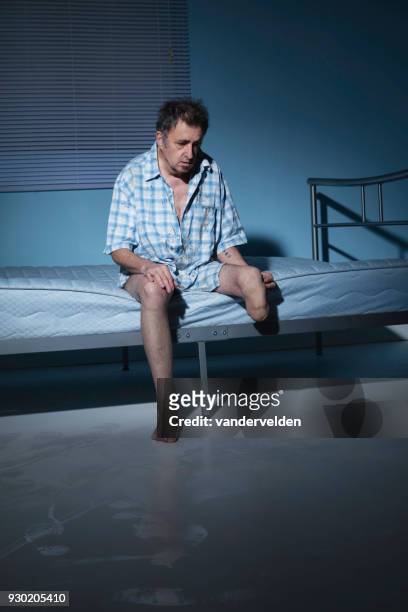 depressed, one-legged man in his stark room - vandervelden stock pictures, royalty-free photos & images