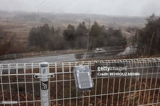 In this picture taken on March 5 a geiger counter by the Safecast non-governmental organisation is attached to a fence near the Dai-ichi power plant...