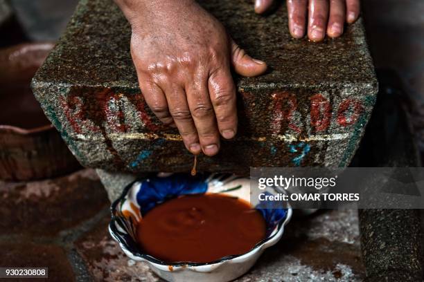 In this file photo taken on February 25 chef Rufina Mendoza grinds chilcosle chili pepper with a metate - a traditional grinding stone - before...
