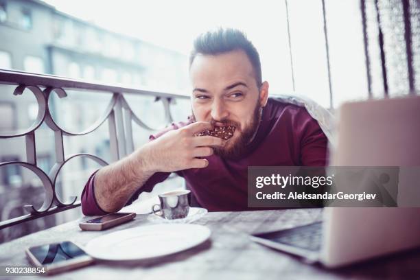 seine ersten morgenkaffee vor laptop trinken auf balkon - friends donut stock-fotos und bilder