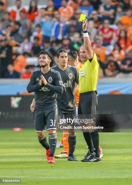 Referee Ted Unkel issues a yellow card to Vancouver Whitecaps midfielder Russell Teibert during the soccer match between the Vancouver Whitecaps and...