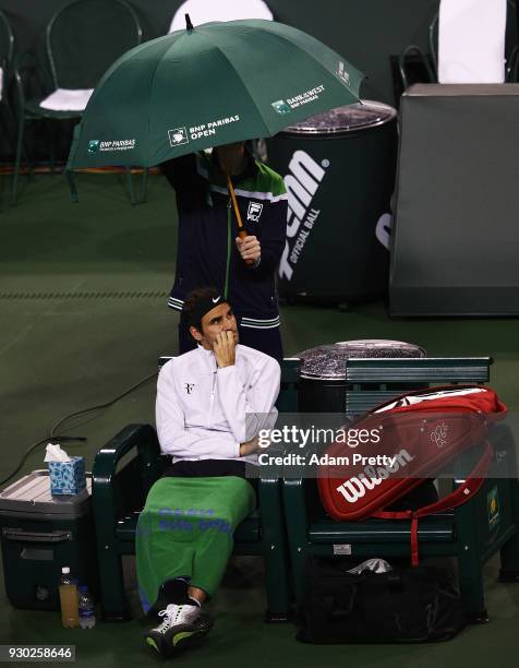 Roger Federer of Switzerland waits for the rain to clear during his match against Federico Delbonis of Argentina during the BNP Paribas Open at the...