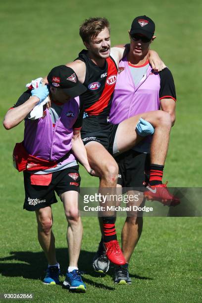 Martin Gleeson of the Bombers is carried off after sustaining a leg injury when landing in a contest for the ball against Cameron Guthrie of the Cats...