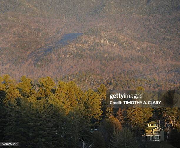 House on Mirror Lake in Lake Placid, New York, is dwarfed by the trees and mountain range behind it November 12, 2009. Lake Placid is hosting Skate...