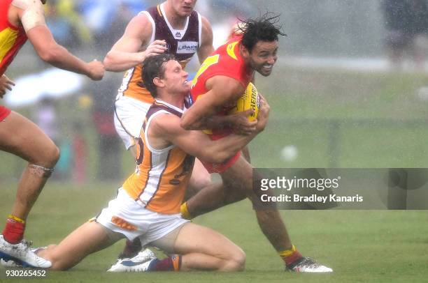 Lachie Weller of the Suns is pressured by the defence during the JLT Community Series AFL match between the Gold Coast Suns and the Brisbane Lions at...