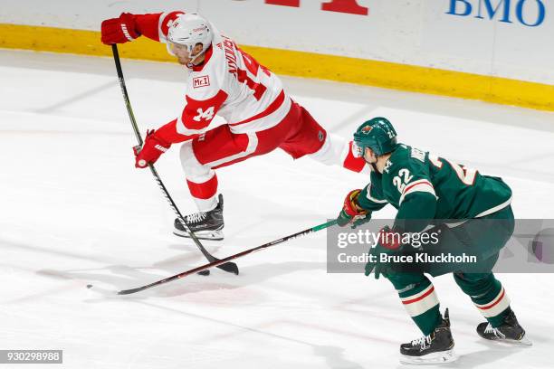 Gustav Nyquist of the Detroit Red Wings shoots the puck with Nino Niederreiter of the Minnesota Wild defending during the game at the Xcel Energy...