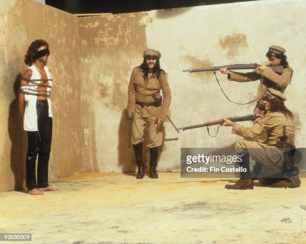 Posed group portrait of Motorhead in mock firing squad scene with Lemmy centre in July 1984. Left to Right: Pete Gill, Lemmy, Phil Campbell and Mick...