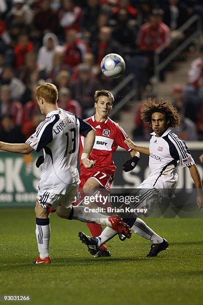 Chris Rolfe of the Chicago Fire kicks the ball past Kevin Alston and Jeff Larentowicz of the New England Revolution during the second half of game 2...