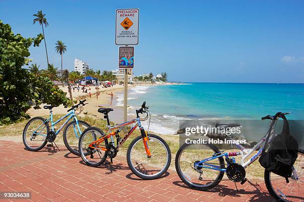 bicycles parked on the path at the seaside, san juan, puerto rico - condado beach stock pictures, royalty-free photos & images