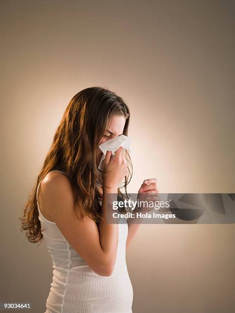 woman blowing her nose - closeup of a hispanic woman sneezing foto e immagini stock