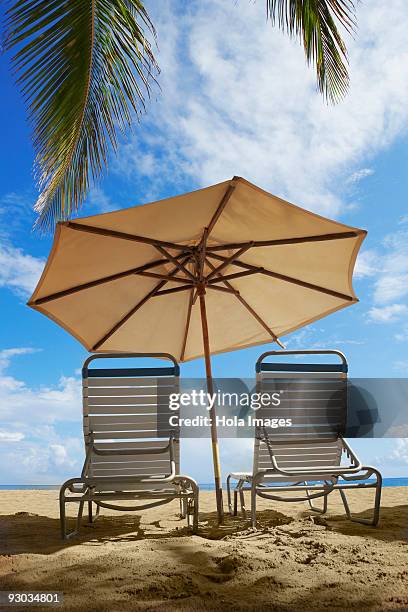 two outdoor chairs and a beach umbrella on the beach, ocean park, el condado, san juan, puerto rico - condado beach stock pictures, royalty-free photos & images