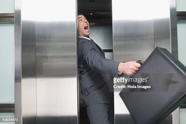 businessman wedged between elevator doors - bloccato foto e immagini stock