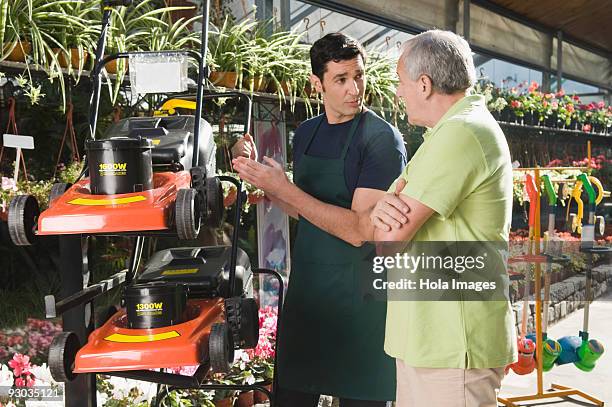 man explaining about a lawn mower to a customer - natuurkunde stock-fotos und bilder