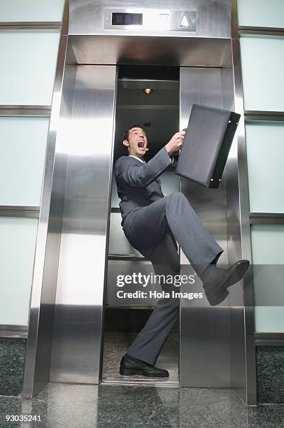 businessman wedged between elevator doors - high sticking stock pictures, royalty-free photos & images