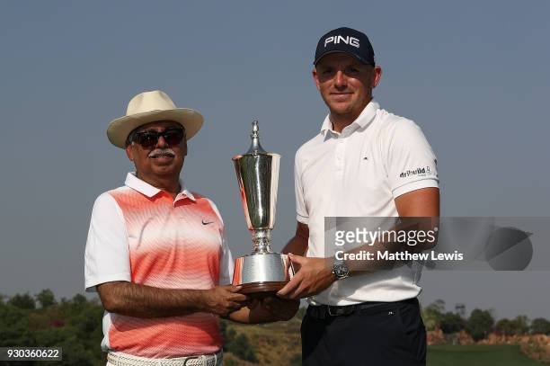 Matt Wallace of England is presented with the trophy by Chairman of Hero MotoCorp Pawan Munjal after winning the play off during day four of The Hero...