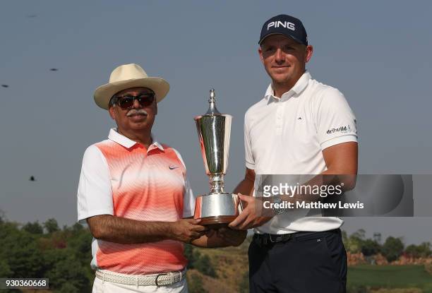 Matt Wallace of England is presented with the trophy by Chairman of Hero MotoCorp Pawan Munjal after winning the play off during day four of The Hero...