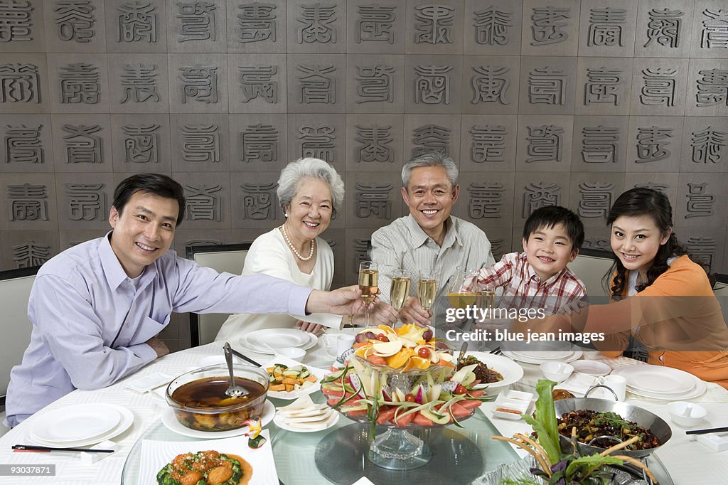 Parents and grandparents with son toasting at dinner table