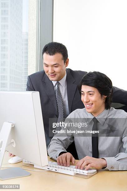 man in business suit shows young employee something on a computer. - man reliable learning stockfoto's en -beelden