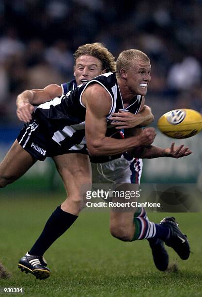 Tarkyn Lockyer of Collingwood attempts to handpass while he is tackled by Shaun McManus of Fremantle, during the match between the Collingwood...