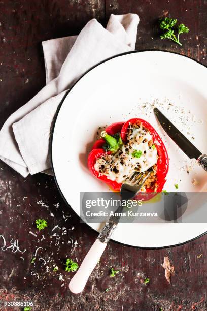 red bell pepper stuffed with pork and beef meat, carrot, onion with grated cheese sprinkled with spices and fresh parsley in a plate on a wooden table, top view - roasted red onion fotografías e imágenes de stock