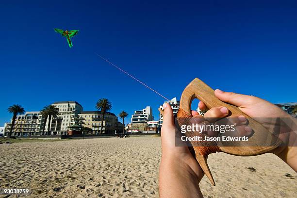 the hands of a young boy flying a bright green balinese dragon kite. - indonesian kite stock pictures, royalty-free photos & images
