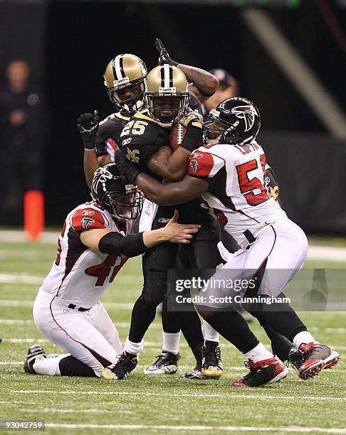 Reggie Bush of the New Orleans Saints is tackled by Curtis Lofton and Mike Schneck of the Atlanta Falcons at the Louisiana Superdome on November 2,...