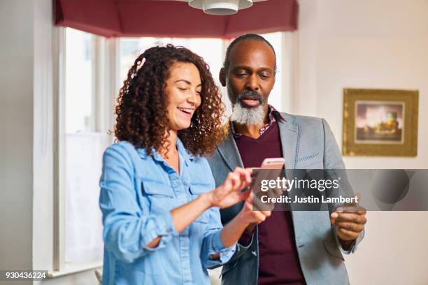 woman showing family member something on their phone at home - phone comparison stock pictures, royalty-free photos & images