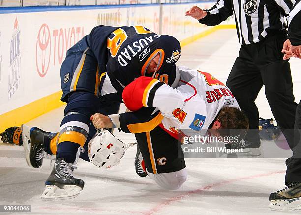 Paul Gaustad of the Buffalo Sabres tries to look through the collar of his jersey while fighting with Dion Phaneuf of the Calgary Flames on November...