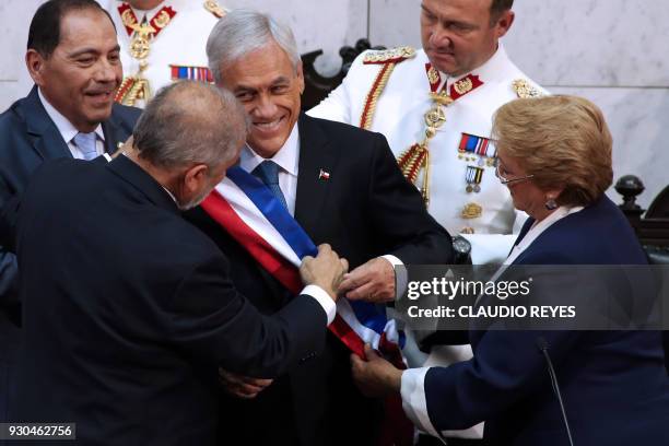 Chile's new President Sebastian Pinera receives the presidential sash from Senate President Carlos Montes while outgoing President Michelle Bachelet...