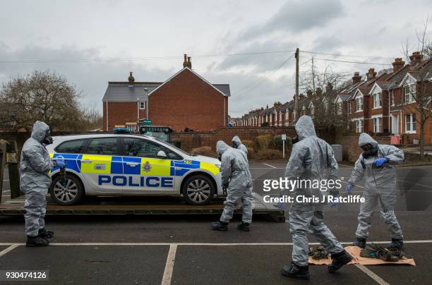 Military personnel wearing protective suits remove a police car and other vehicles from a public park as they continue investigations into the...