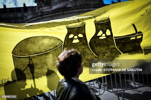 An environmental activist walks past a banner during a demonstration called by associations to mark the seventh anniversary of the Fukushima nuclear...