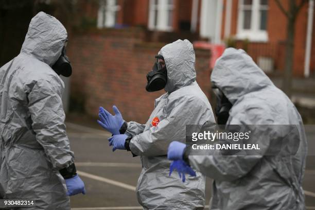 Military personnel wearing protective coveralls work to remove vehicles from a cordoned off area behind a police station in Salisbury, southern...