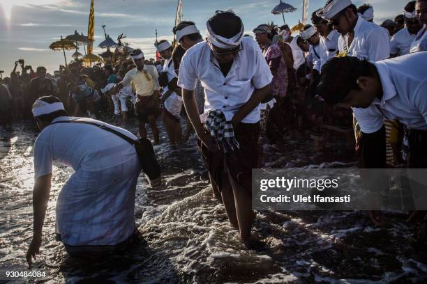 Hindus devotees prepare wash their faces with sea water as they pray during the Melasti ritual ceremony at Parangkusumo beach on March 11, 2018 in...