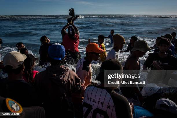 Villagers trying to catch a chicken after being thrown by Hindu worshippers as an offering during the Melasti ritual ceremony at Parangkusumo beach...