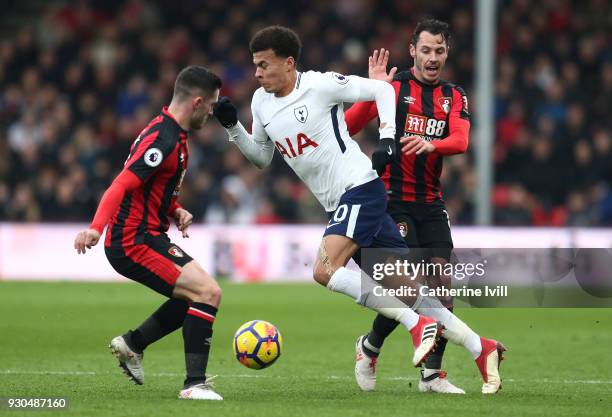 Dele Alli of Tottenham Hotspur is challenged by Adam Smith of AFC Bournemouth and Lewis Cook of AFC Bournemouth during the Premier League match...