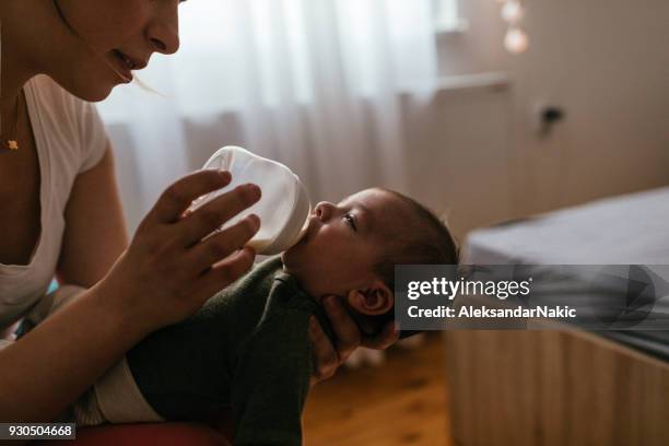 mamma che nutre il suo neonato - baby bottle foto e immagini stock