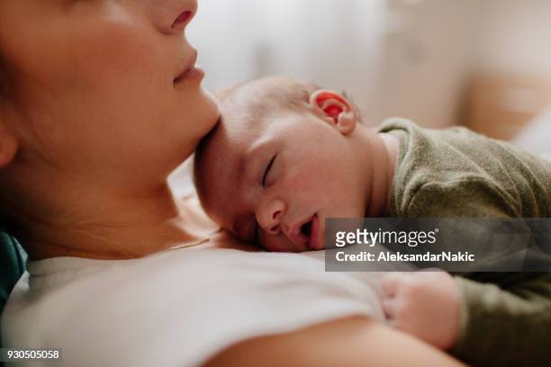 madre che mette a dormire il suo bambino - bebé foto e immagini stock