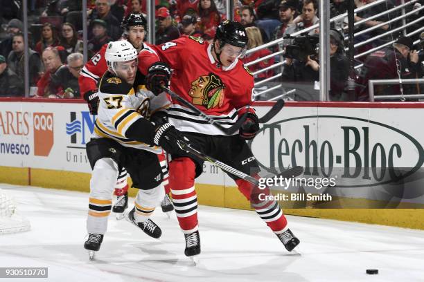 Tommy Wingels of the Boston Bruins and David Kampf of the Chicago Blackhawks chase the puck in the second period at the United Center on March 11,...
