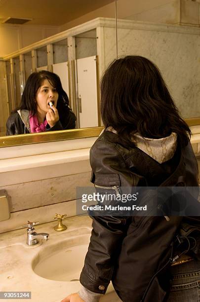young woman putting on lipstick in public washroom - woman lipstick rearview stock pictures, royalty-free photos & images