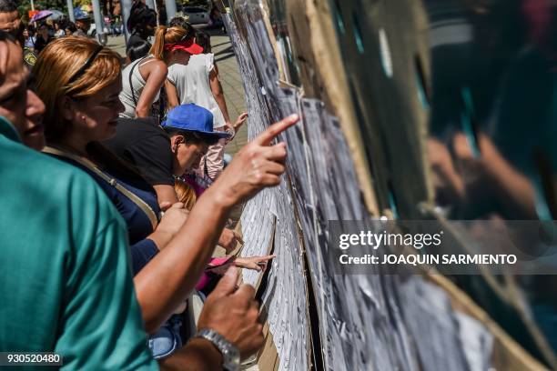 People check the electoral roll at a polling station in Medellin, Antioquia Department, during parliamentary elections in Colombia on March 11, 2018....