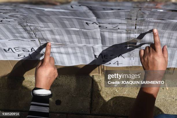 Women check the electoral roll at a polling station in Medellin, Antioquia Department, during parliamentary elections in Colombia on March 11, 2018....